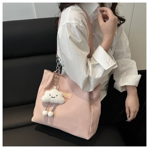 Detail view of pink corduroy tote bag featuring a cute cloud charm and leather label