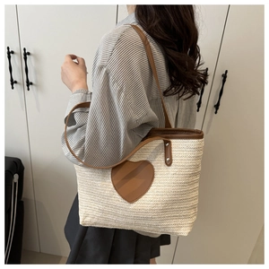 Détail du sac cabas tissé avec patch cœur en cuir marron et bandoulières robustes