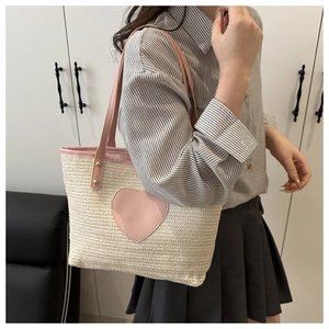 Détail du sac cabas en paille tressée avec écusson cœur rose et anses en cuir