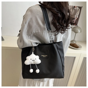 Detail of black corduroy tote bag featuring chain strap and cute cloud plush charm