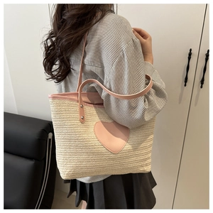 Détail du sac seau en paille avec patch coeur en cuir rose et bandoulière réglable
