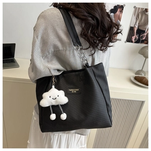 Detail of black textured tote bag featuring a metal chain strap and white plush cloud charm