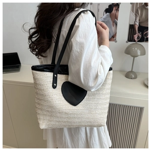 Détail du sac seau en paille avec un patch coeur en cuir noir et texture tissée
