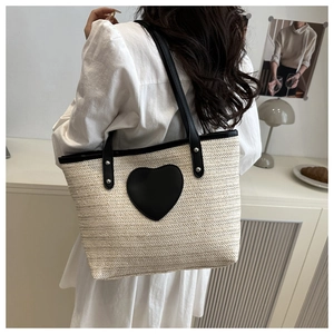 Détail du sac cabas tissé beige avec cœur en cuir noir et rivets sur les poignées