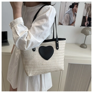 Détail du sac cabas en paille crème avec patch coeur en cuir noir et fine bandoulière