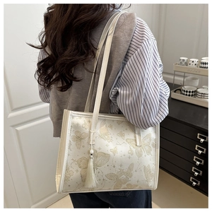 Dettaglio dell'elegante borsa tote bianco sporco con stampe a farfalla e nappa decorativa