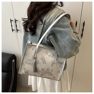 Dettaglio borsa shopper con stampa a farfalla, spalline argento e ciondolo a nappa grigio