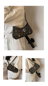 Detail of black crescent shoulder bag with silver buckle straps and punk eyelet design