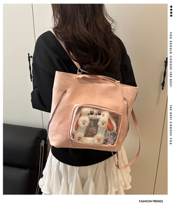Detailed view of pink Ita bag with clear window showing plush toys and decorative badges