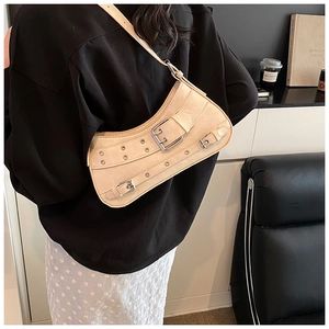 Detail of beige Y2K underarm bag with metal buckles and eyelets on suede-like texture