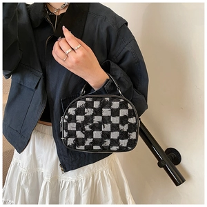 Detail of checkered mini bag featuring raw fringe edges and black leather handle strap