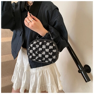 Detail of checkered tweed crossbody bag with fringe edges and silver zipper hardware