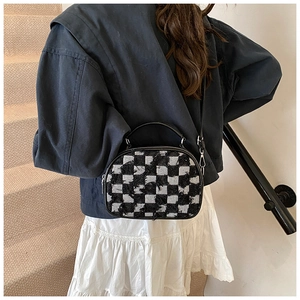 Detailed close-up of a checkered pattern crossbody bag with fringe texture and metal zipper
