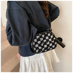 Detail of checkered tweed crossbody bag showing the frayed edges and leather handle