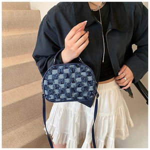 Detail of blue checkerboard denim crossbody bag with raw edges and silver hardware