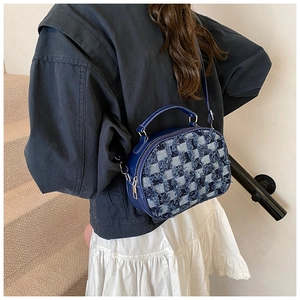 Detailed view of dark blue plaid crossbody bag with frayed denim and leather accents
