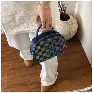 Detail of colorful tweed plaid bag with frayed edges and premium blue leather handle