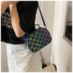 Detail of denim crossbody bag featuring colorful plaid patchwork and frayed edge texture
