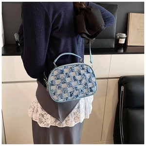 Close-up of a blue denim crossbody bag with checkerboard pattern and fringe detailing
