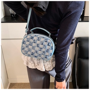 Detail of light blue denim shell bag showing fringe edges and checkered texture
