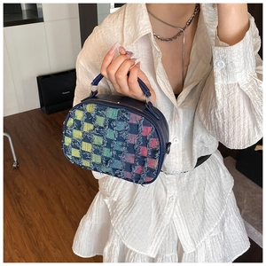 Detail of color-block checkered denim bag with distressed frayed edges and top handle