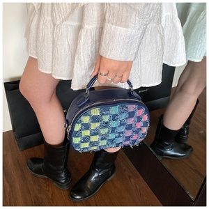 Detail of colorful plaid shell bag with fringed edges and silver hardware accents