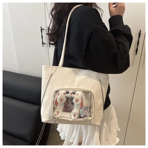 Detailed close-up of a white ita bag featuring a transparent window with anime badges