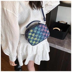 Model wearing a blue shell-shaped handbag with colorful distressed check texture