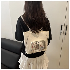 Détail du sac ita blanc crème montrant la grande fenêtre transparente et les bandoulières