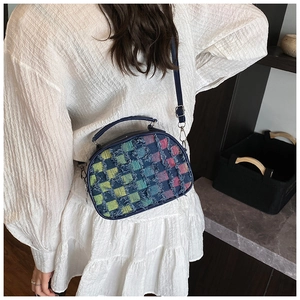 Detail of colorful woven plaid crossbody bag with trendy frayed edges and blue handle