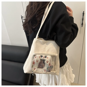 Détail du sac ita en toile crème avec poche PVC montrant une peluche lapin et des badges