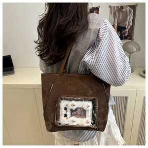 Detail of dark brown tote bag with transparent window and cute white plush cat accessory