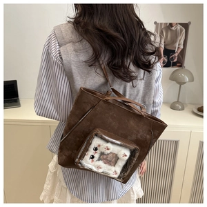 Detail of dark brown suede shoulder bag with transparent window and plush cat-themed decor