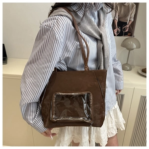 Détail d'un sac ita en daim marron avec fenêtre transparente et fermetures éclair latérales