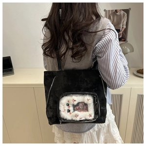 Close-up of black suede tote bag featuring a transparent window and plush cat charm