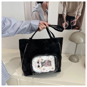 Detail of black suede ita bag featuring a clear window with a plush cat insert