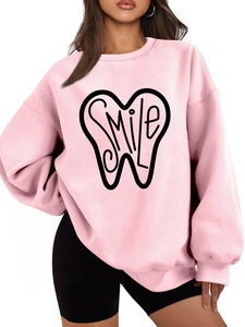 Detail of pink crewneck sweatshirt featuring a black SMILE tooth graphic and soft fabric