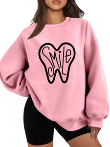Close-up of pink oversized sweatshirt featuring a black smile graphic with artistic lettering