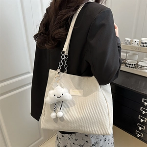 Large beige corduroy tote bag with chain strap and cute cloud charm shown on shoulder