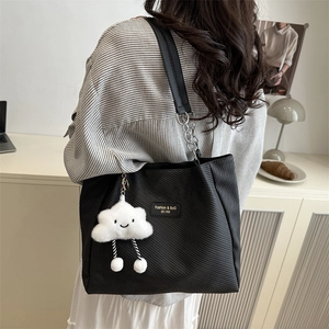 Large black canvas tote bag with chain strap and white cloud charm shown on model