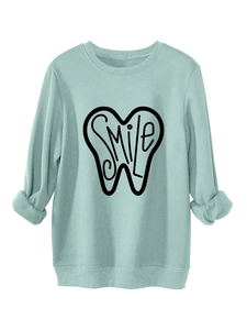 Detail of mint green sweatshirt featuring black smile tooth graphic and folded cuffs