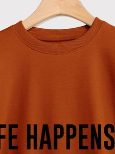 Close-up of the ribbed crew neck and black letter print on a caramel sweatshirt