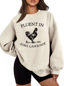 Close-up of rooster illustration and Fluent in Fowl Language text on beige sweatshirt