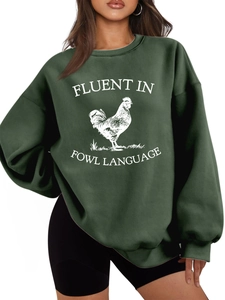 Close-up of 'FLUENT IN FOWL LANGUAGE' text and rooster print on green sweatshirt
