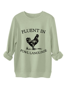 Close-up of the ribbed crew neck and black rooster print on sage green sweatshirt