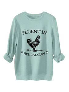 Detailed close-up of mint green sweatshirt with rooster print and fowl language text