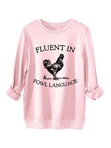 Detailed close-up of pink crewneck sweatshirt with 'Fluent in Fowl Language' rooster print