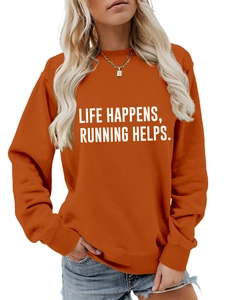 Detail of orange crewneck sweatshirt featuring Life Happens Running Helps slogan text
