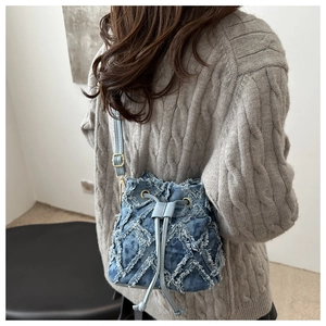 Detailed close-up of blue denim bucket bag featuring quilted tassel fringe texture