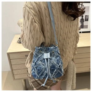 Detail of blue denim bucket bag featuring quilted distressed texture and drawstring